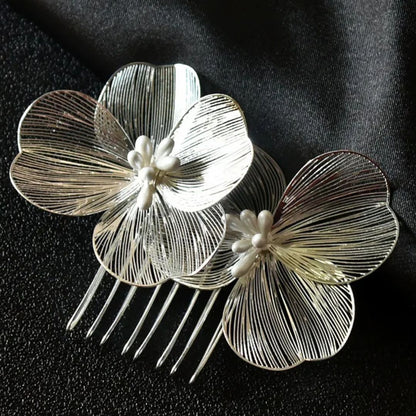 Silberne Haarspange mit filigranen Blumen, Perlenakzenten, elegantes Accessoire auf schwarzem Stoff.