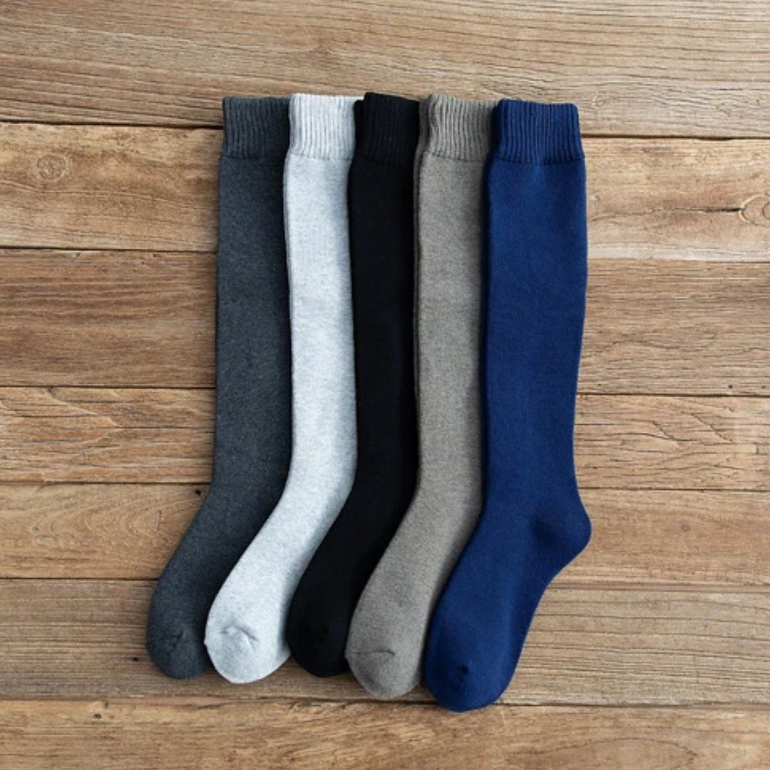 Fünf Paar bunte Kniestrümpfe aus Baumwolle auf Holzboden, ideal für Herbstmode.