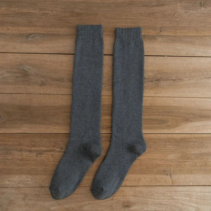 Graue Kniestrümpfe aus Wolle auf Holzboden, warme Winterstrümpfe, gemütliche Socken.