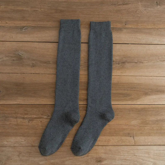 Graue Kniestrümpfe aus Wolle auf Holzboden, warme Winterstrümpfe, gemütliche Socken.