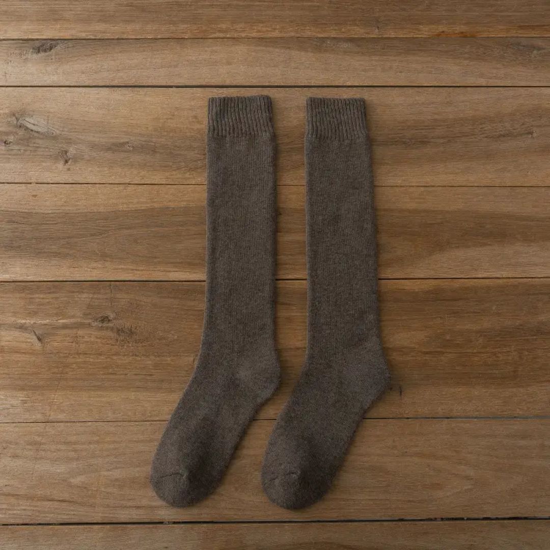 Braune Wollsocken auf Holzboden, knielang, warm, bequem, ideal für Winter, Unisex.
