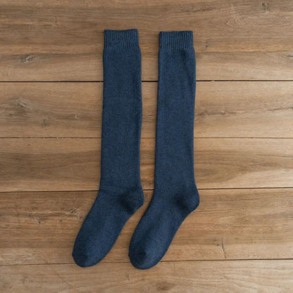Dunkelblaue Kniestrümpfe aus Baumwolle auf Holzboden, bequeme Socken für Damen und Herren.