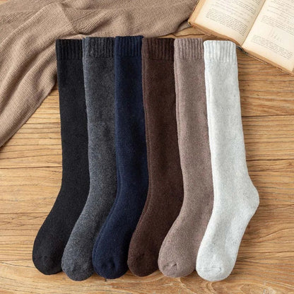 Sechs Paar warme Wollsocken in verschiedenen Farben auf Holzboden, ideal für den Winter.