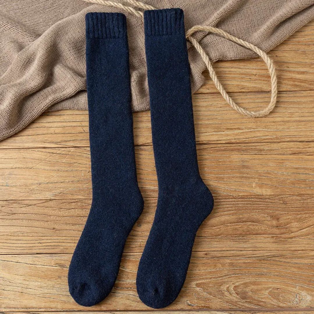 Dunkelblaue Kniestrümpfe aus Wolle auf Holzboden, warme Winterstrümpfe, gemütlich und stilvoll.