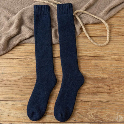Dunkelblaue Kniestrümpfe aus Wolle auf Holzboden, warme Winterstrümpfe, gemütlich und stilvoll.