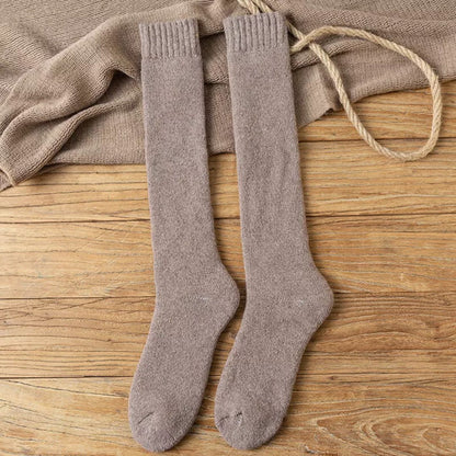 Beige Kniestrümpfe aus Wolle auf Holzboden, warme Winterstrümpfe, gemütliche Socken.