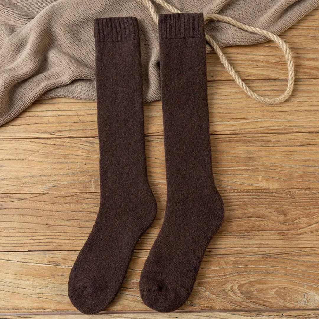 Braune Wollsocken auf Holzboden, warme Strümpfe, gemütliche Winterkleidung, modische Accessoires.