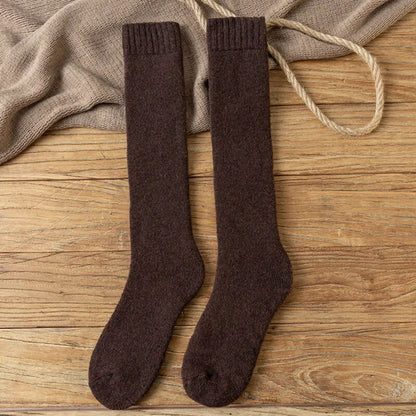 Braune Wollsocken auf Holzboden, warme Strümpfe, gemütliche Winterkleidung, modische Accessoires.