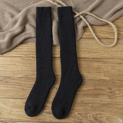 Schwarze Kniestrümpfe aus Baumwolle auf Holzboden, ideal für Herbstmode.