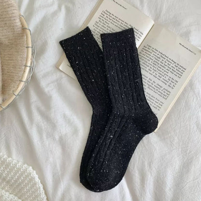 Schwarze Stricksocken auf offenem Buch, gemütliches Design, warme Winterkleidung.