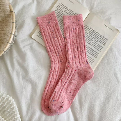 Rosa Stricksocken auf Buch, gemütliche Wollsocken, Damenmode, Herbst-Winter Accessoire.