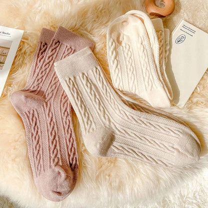 Beige und rosa Stricksocken aus Wolle auf flauschigem Hintergrund, gemütliche Wintermode.