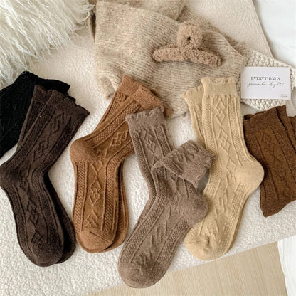 Mehrfarbige Stricksocken aus Wolle, beige, braun, schwarz, auf Bett, gemütlich, Herbstmode.