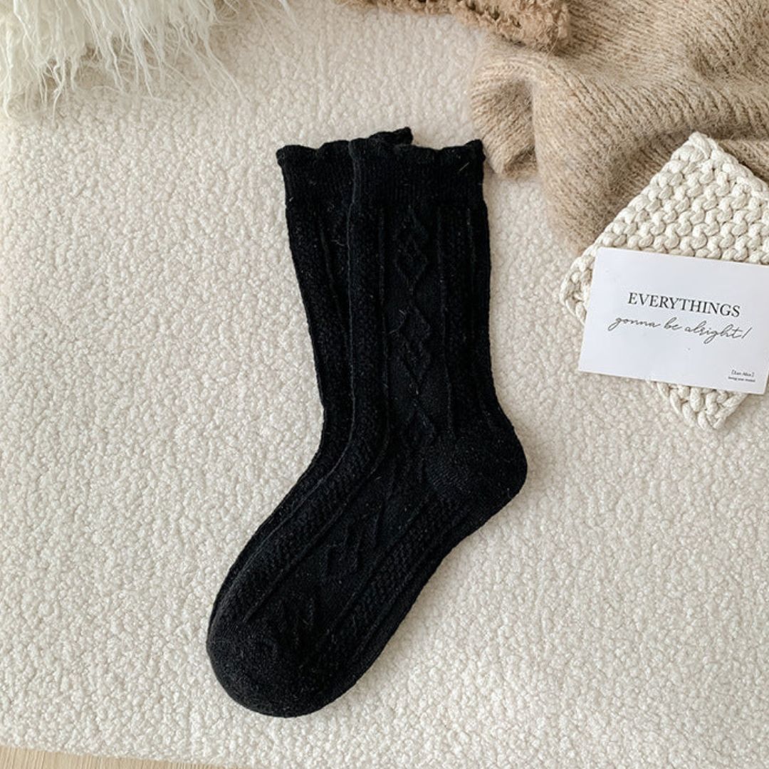 Schwarze Stricksocken aus Wolle auf beigem Hintergrund, gemütlich, warm, modisch.