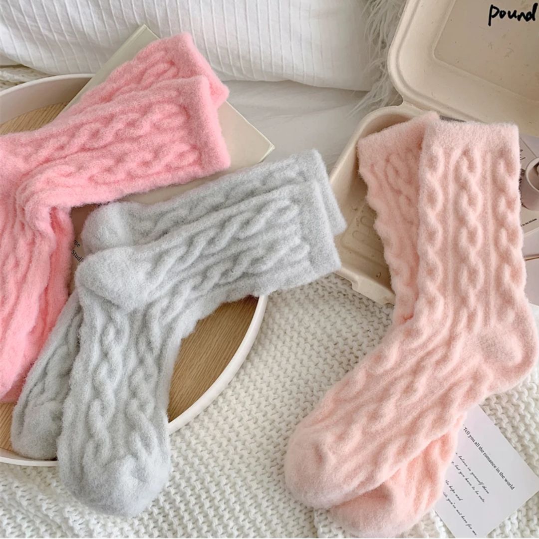 Weiche, flauschige Socken in Rosa und Grau auf weißem Hintergrund, gemütliche Wintermode.