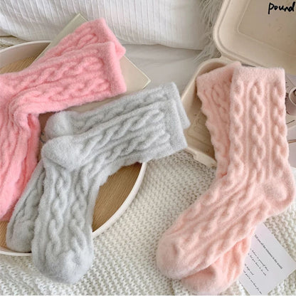 Weiche, flauschige Socken in Rosa und Grau auf weißem Hintergrund, gemütliche Wintermode.