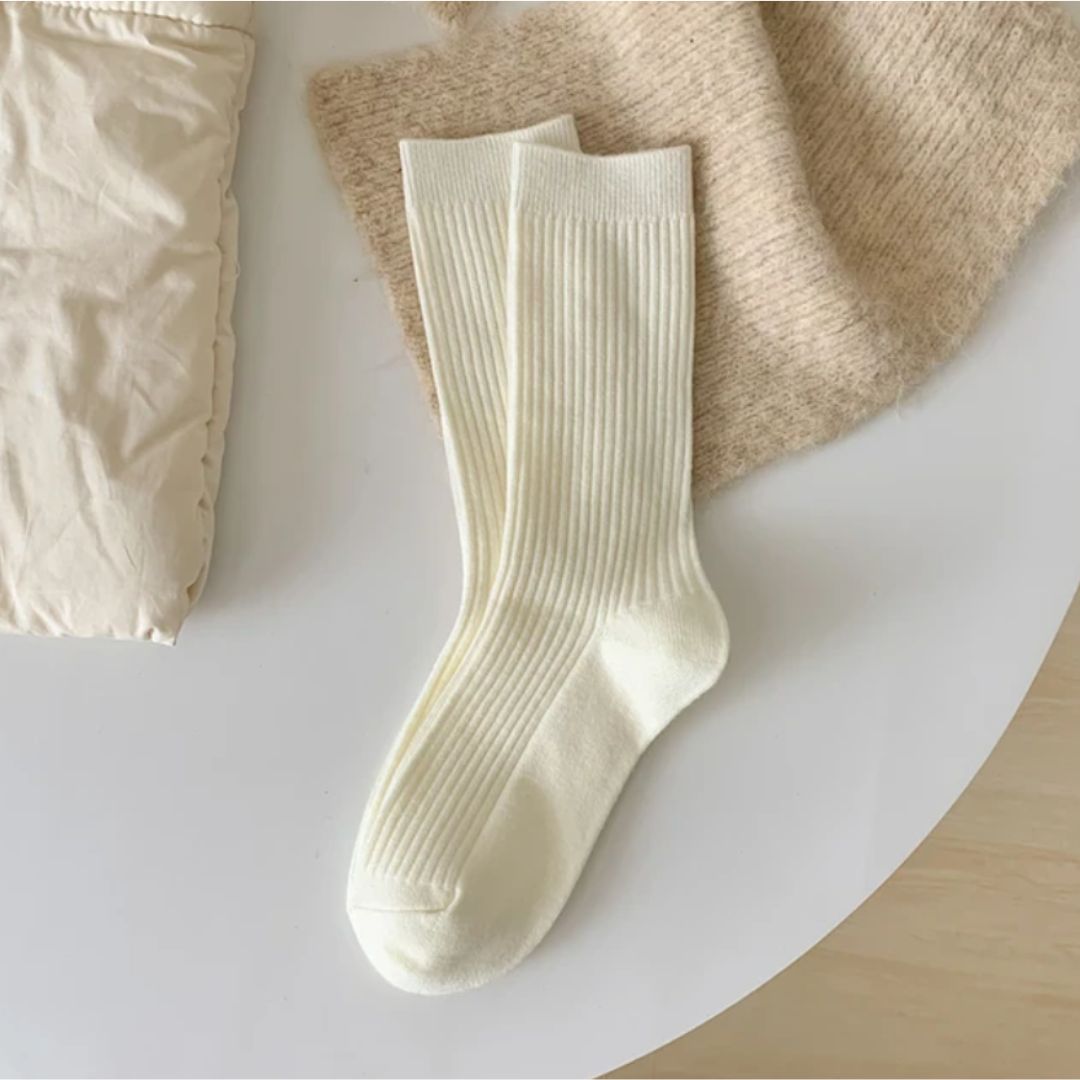 Weiße gerippte Socken aus Baumwolle auf Tisch, gemütlich, modisch, für Damen und Herren.
