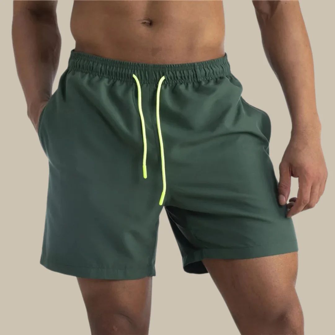 Mann in grüner Badehose mit gelbem Kordelzug, sportlich, Strandmode, Herrenbekleidung.