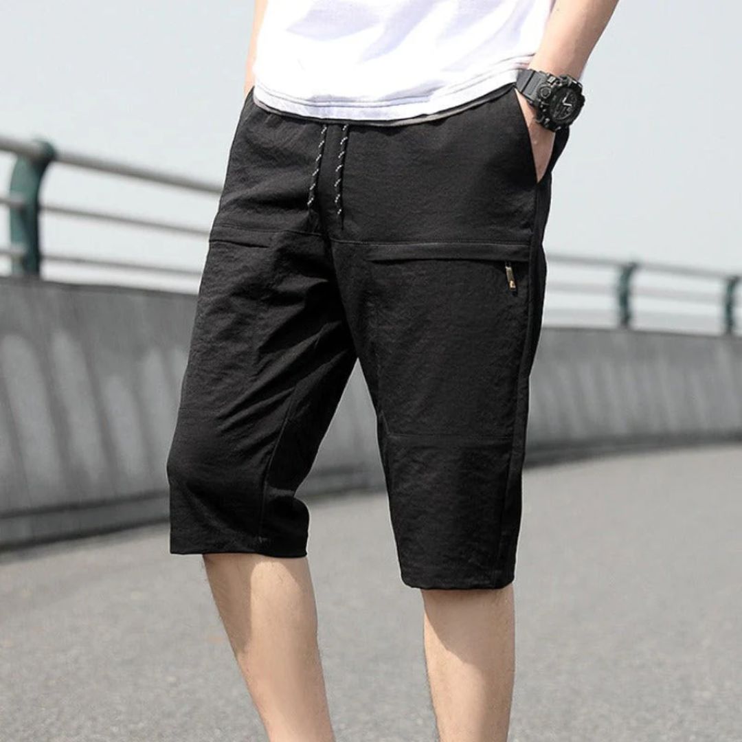 Mann in schwarzen Cargo-Shorts aus Baumwolle auf Brücke, lässiger Sommerstil.