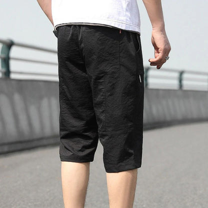 Mann in schwarzen Baumwoll-Shorts auf Straße, lässige Sommermode, Rückansicht.