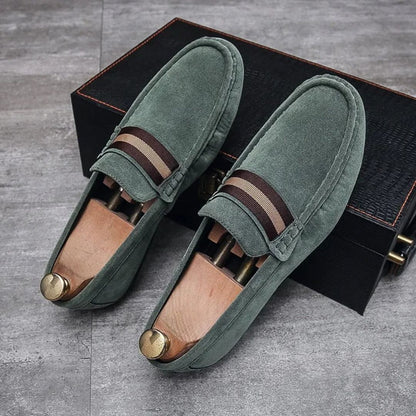 Grüne Wildleder-Loafer mit Holzschuhspanner, Herrenschuhe, elegantes Design, auf grauem Boden.