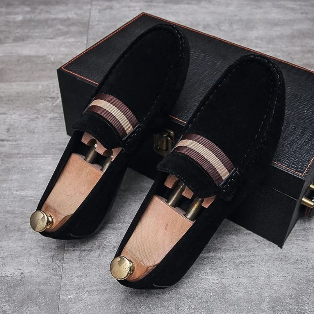 Schwarze Wildleder-Loafer mit Holzschuhspanner auf grauem Boden, elegante Herrenschuhe.