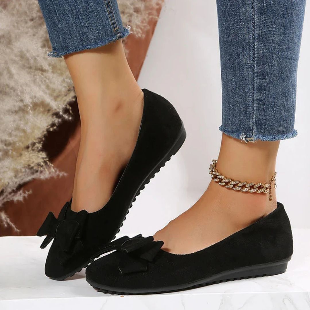 Schwarze Damen-Ballerinas aus Wildleder mit Schleife, kombiniert mit blauen Jeans.