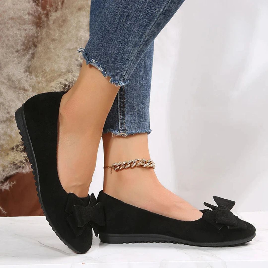 Schwarze Damen-Ballerinas mit Schleife, Wildlederoptik, kombiniert mit blauer Jeans.