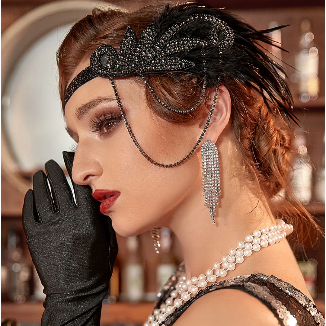 Frau im 1920er-Jahre-Stil mit schwarzem Stirnband, Perlenkette, langen Ohrringen und Handschuhen.