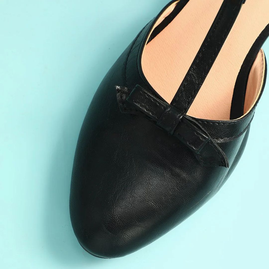 Schwarzer Damen-Ballerina aus Leder mit Schleife auf blauem Hintergrund.