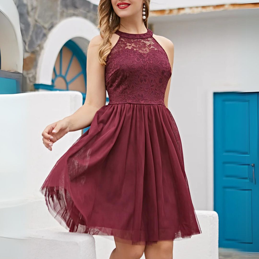 Frau in burgunderrotem Spitzenkleid, ärmellos, vor blauen Türen, elegantes Sommeroutfit.