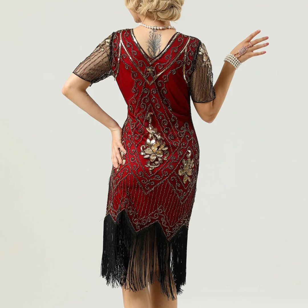 Frau in rotem, besticktem Charleston-Kleid mit Fransen und Perlenkette, Rückansicht.
