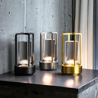 Drei moderne LED-Tischlampen in Schwarz, Silber und Gold auf Betonoberfläche.