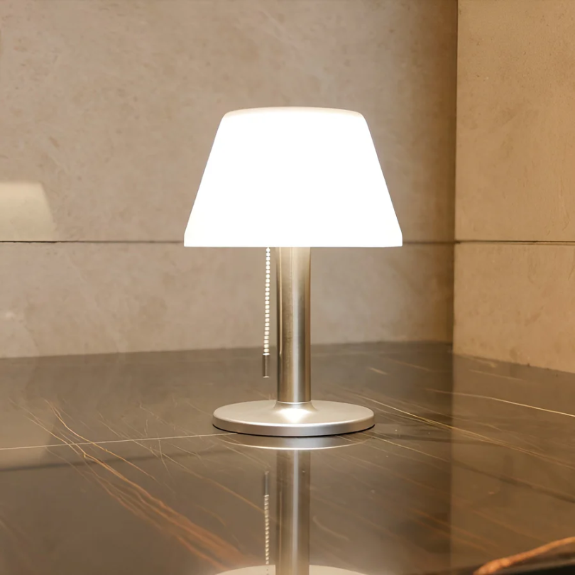 Moderne Tischlampe aus Metall mit weißem Schirm auf Marmortisch, Innenbeleuchtung.