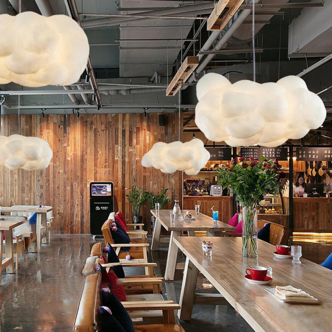 Moderne Café-Innenraum mit Wolkenlampen, Holztischen und gemütlicher Atmosphäre.