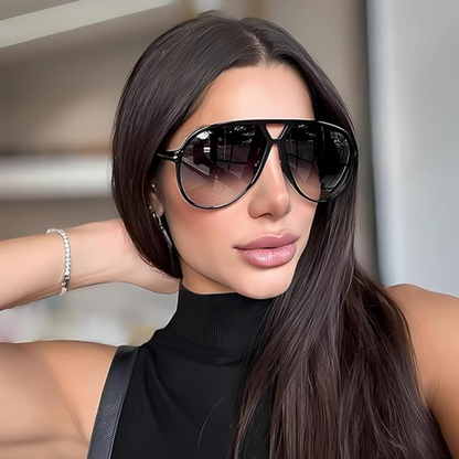Frau mit schwarzer Sonnenbrille, langem braunem Haar, schwarzem Top, modisch, elegant.