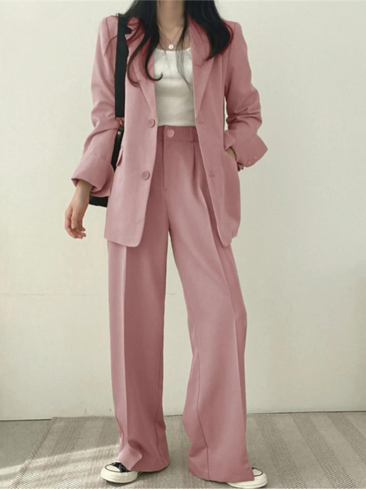 Frau in rosa Anzug mit weißem Top und Sneakers, modisch, elegant, Business-Look.