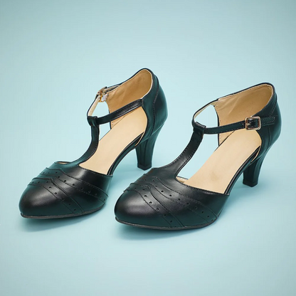 Schwarze Damen-T-Steg-Pumps aus Leder mit mittlerem Absatz auf blauem Hintergrund.