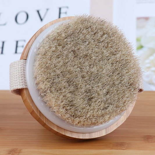 Runde Trockenbürste aus Holz mit Naturborsten auf Holzoberfläche, Wellness-Accessoire.