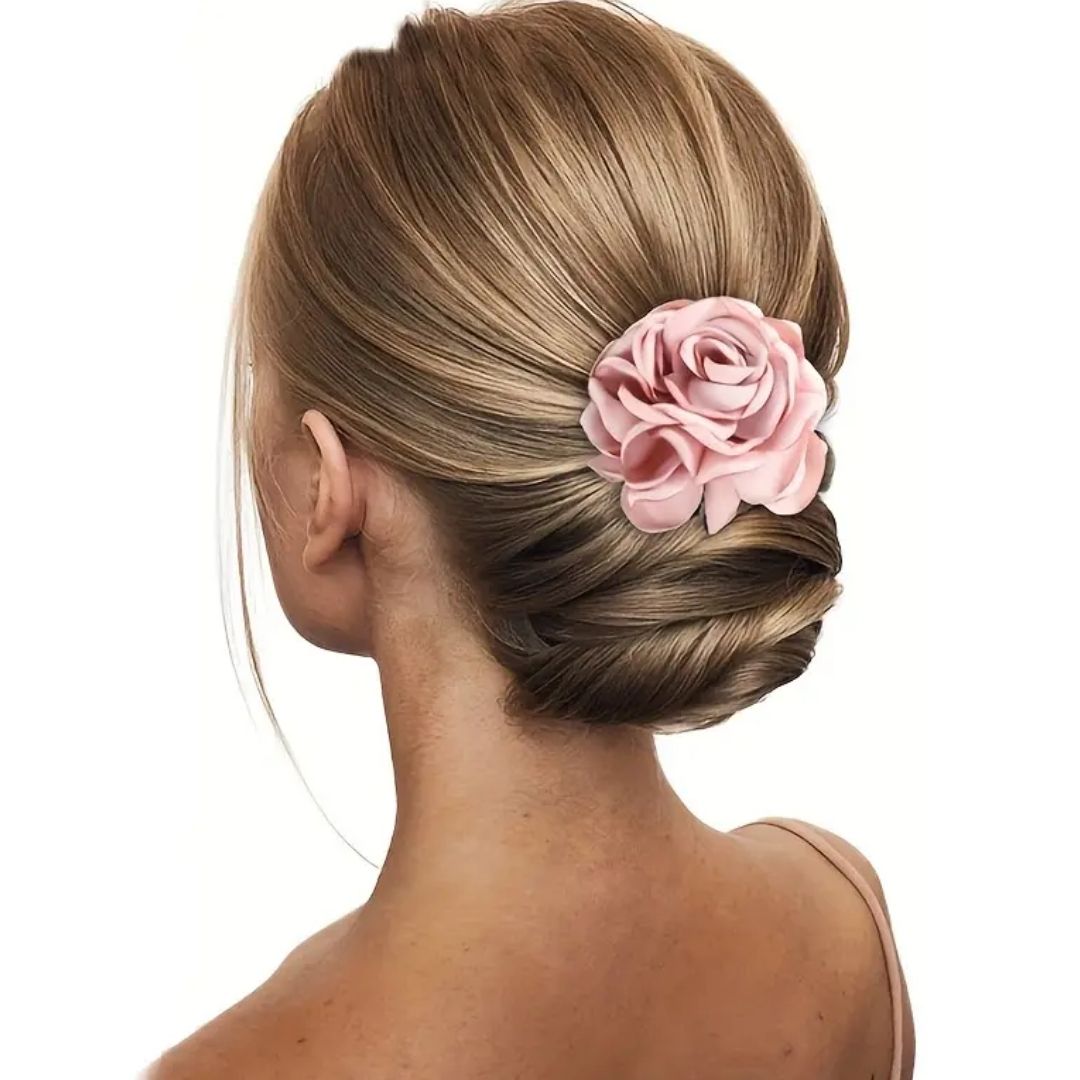 Frau mit elegantem Dutt und rosa Rosen-Haarspange, Hochzeitsfrisur, Brautaccessoire.