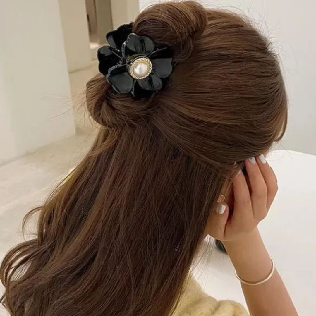 Frau mit braunem Haar, schwarze Haarspange mit Perle, elegantes Accessoire, Frisur.