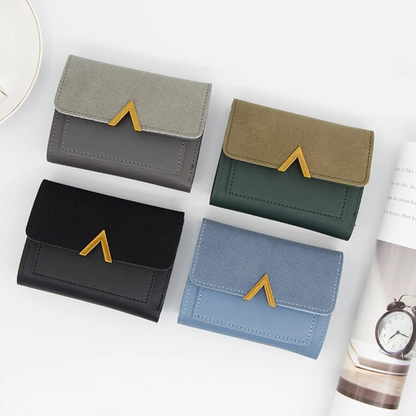 Vier Mini-Geldbörsen aus Samt und Leder in Grau, Grün, Schwarz und Blau mit goldenen Details.
