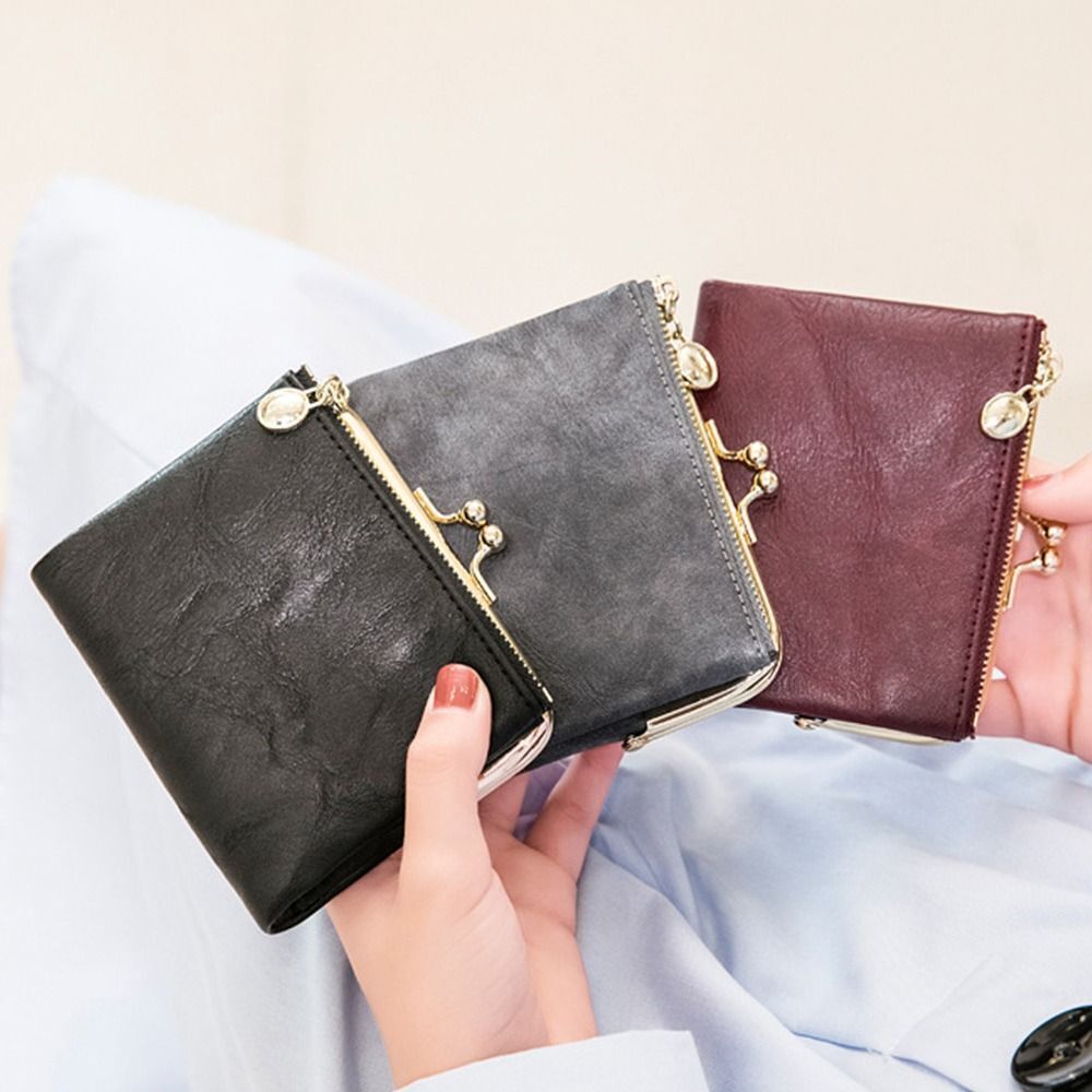 Drei Vintage-Kisslock-Geldbörsen aus Leder in Schwarz, Grau und Braun, elegant und kompakt.