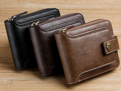 Drei Vintage-Leder-Geldbörsen in Schwarz, Braun und Dunkelbraun auf Holzoberfläche.