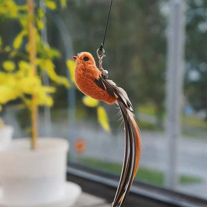 Orangefarbener Deko-Vogel mit langem Schwanz, hängend, Fensterhintergrund, künstlich, realistisch.