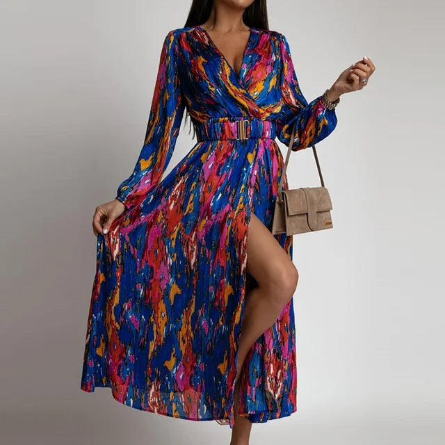 Frau in bunter Vintage-Kleid mit V-Ausschnitt, Laternärmeln und Schlitz, hält braune Tasche.