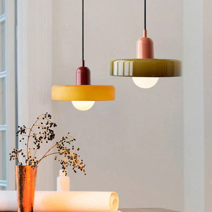 Zwei moderne Hängelampen, gelb und grün, aus Keramik über einem Tisch, skandinavisches Design.