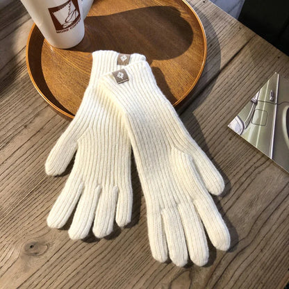 Weiße Strickhandschuhe aus Wolle auf Holztisch, ideal für Wintermode und kaltes Wetter.