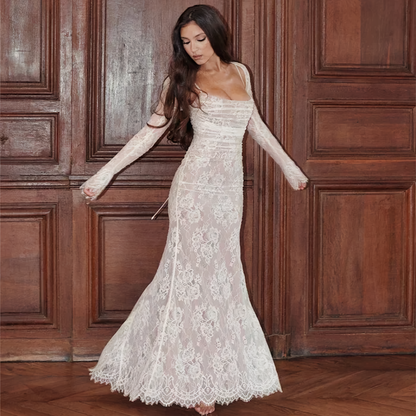 Frau in weißem Spitzenkleid, langärmelig, figurbetont, vor Holztüren, elegante Abendmode.