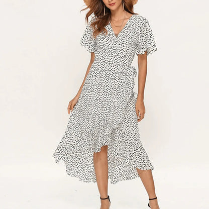 Frau in weißem gepunktetem Sommerkleid, V-Ausschnitt, Rüschen, knielang, modisch, elegant.